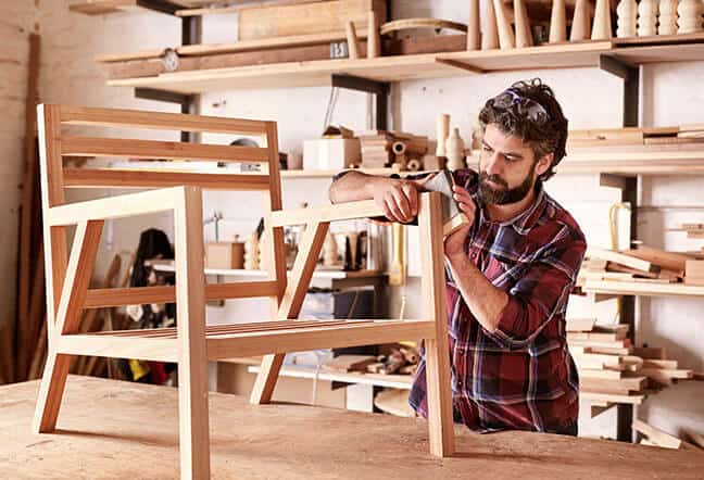 imagen de empresario tallando una silla de madera