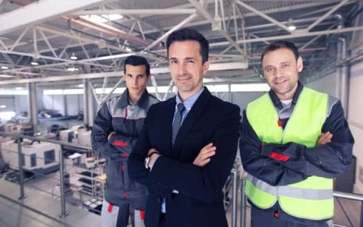 imagen de tres personas con ropa de trabajo fondo industrial